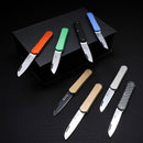 Collection of compact folding knives with various colored handles and stainless steel blades displayed on black surface