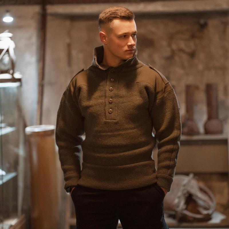 Man wearing olive green Austrian Army Alpine wool pullover sweater with high collar in rustic indoor setting