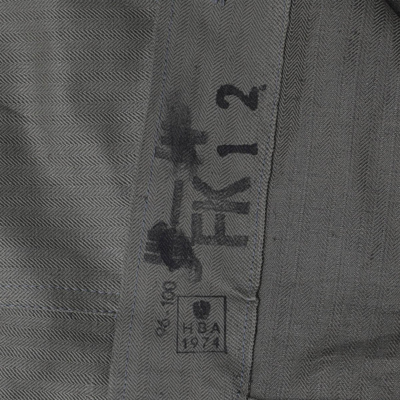 Close-up of vintage Austrian M59 field jacket fabric showing black stenciled military markings and herringbone pattern.