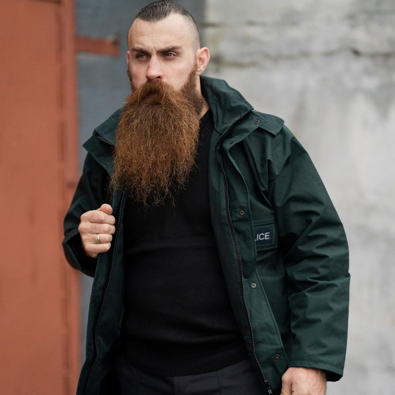 Man wearing original British police waterproof green anorak parka with hood and adjustable cuffs outdoors
