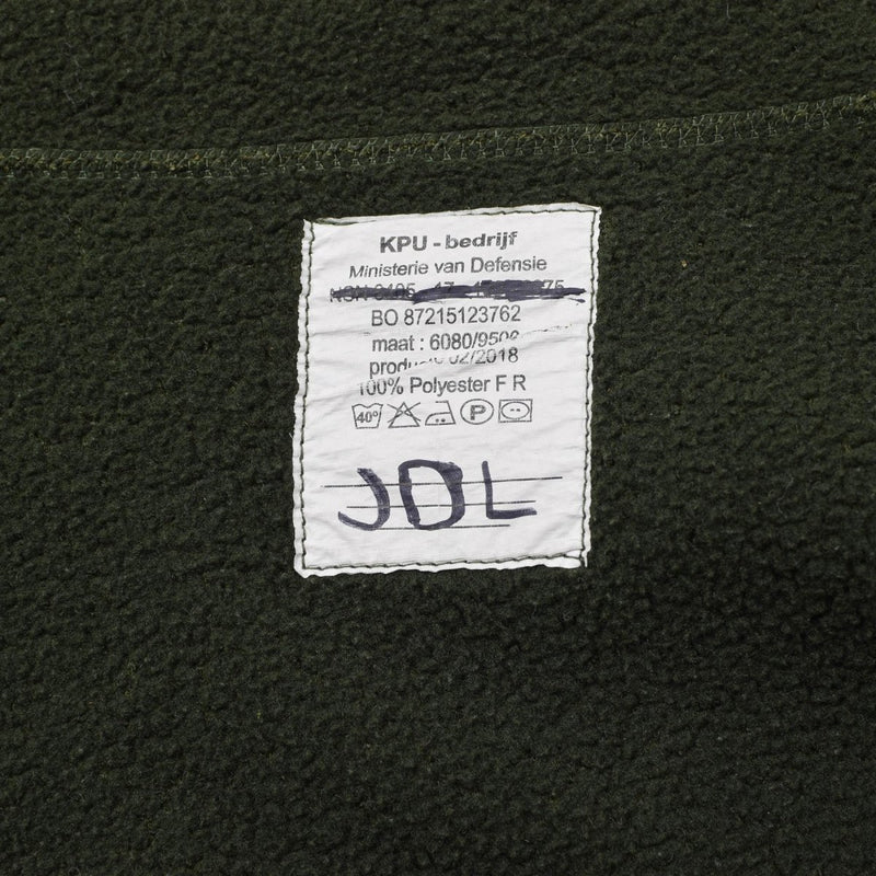 Close-up of olive green Dutch Military fleece jacket label showing fabric and care instructions on soft thermal material