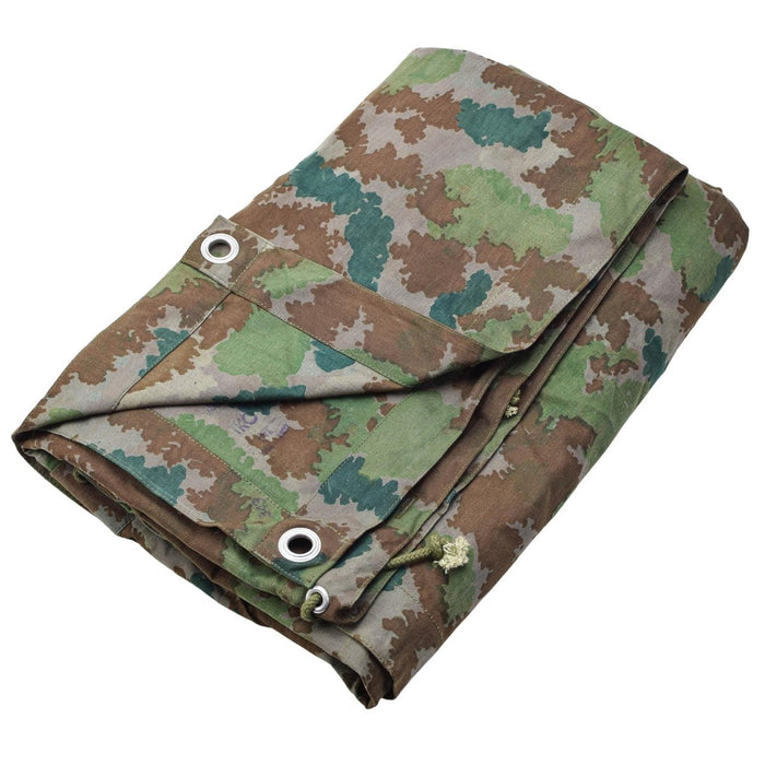 Folded vintage German military camouflage poncho tent with metal grommets for camping or survival shelter use