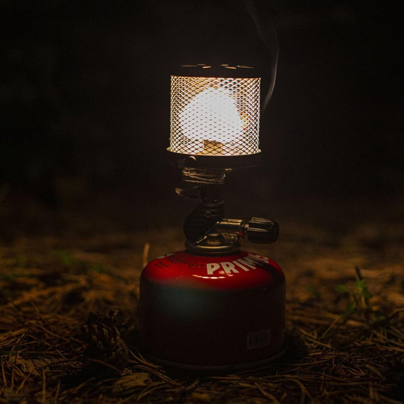 Primus Micron gas lamp lantern glowing with adjustable brightness on red fuel canister outdoors at night